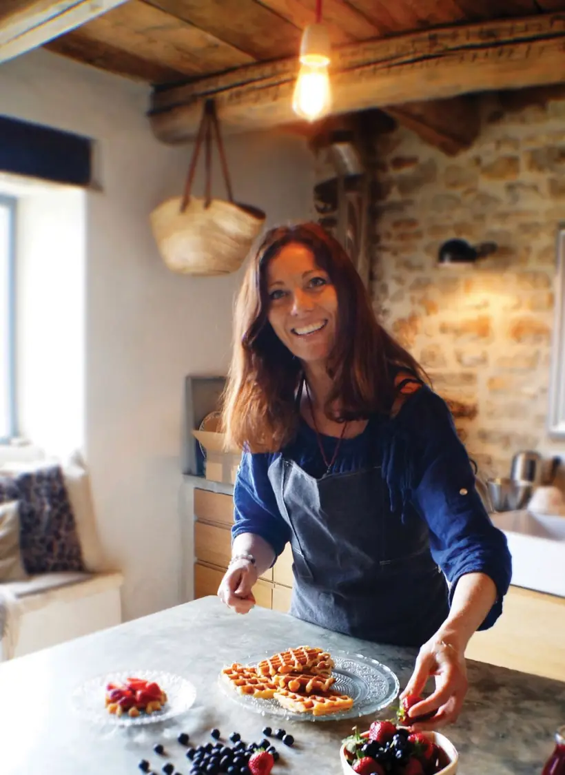 Frédérique Barral souriante dans sa cuisine, dressant une assiette de fruits rouges